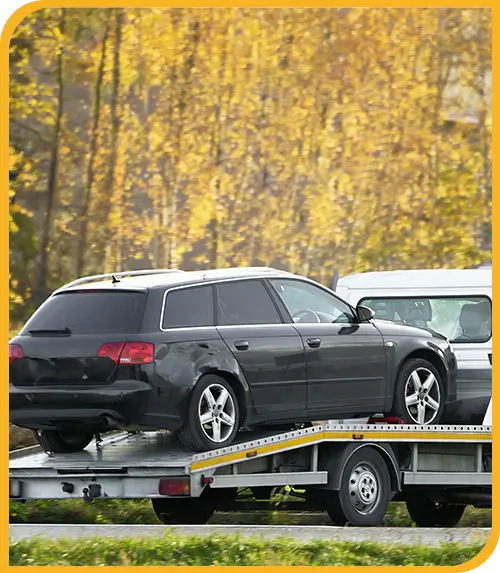 Abschleppwagen transportiert ein Fahrzeug durch herbstliche Landschaft