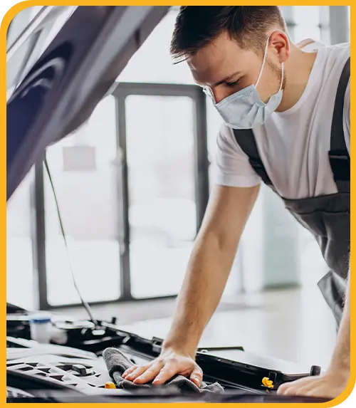 Mechaniker mit Mundschutz arbeitet am Motorraum